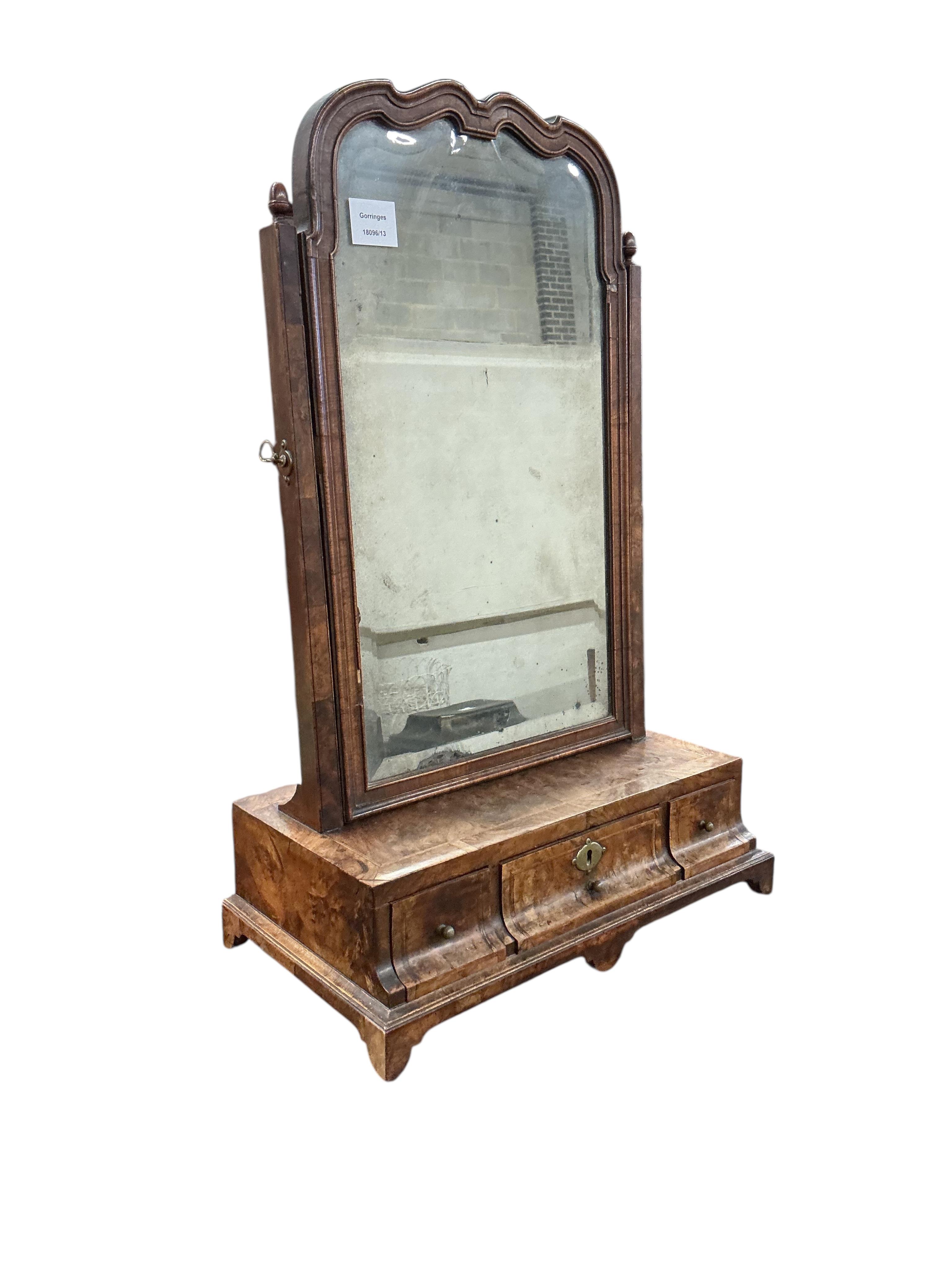 An early 18th century feather banded walnut toilet mirror, with three base drawers, width 44cm, depth 24cm, height 68cm